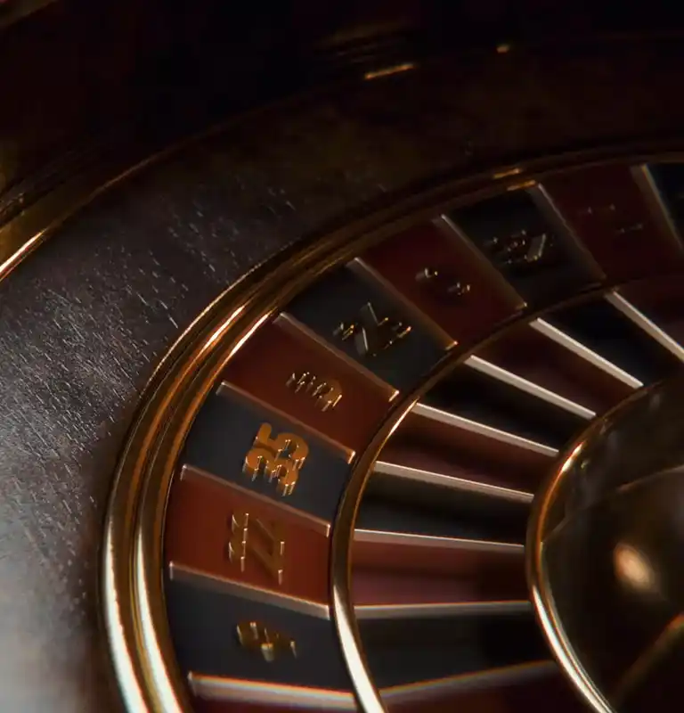 Close-up of a roulette wheel with alternating red and black numbered slots and gold accents.